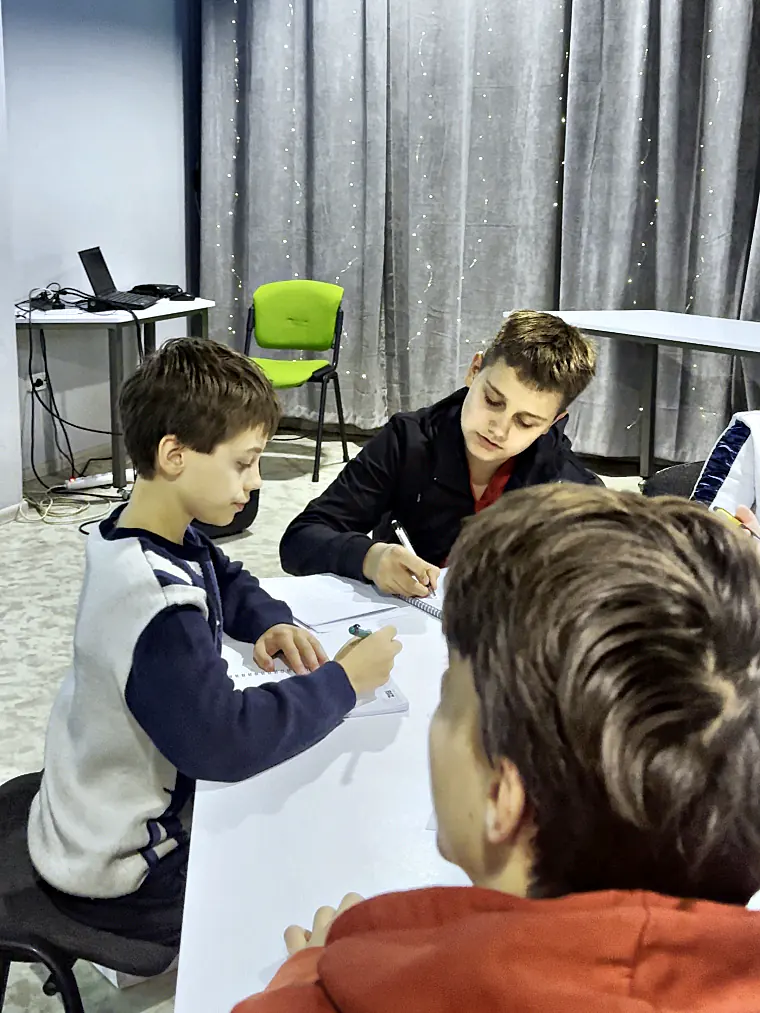 Підлітки разом збирають проєкт із конструктора за столом